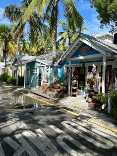 a small blue and white building sitting on the side of a road next to palm trees