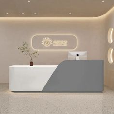 the reception desk is white and has a potted plant on it in front of an illuminated sign