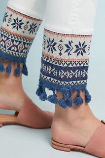 the legs and ankles of a woman wearing sandals with blue tassels on them