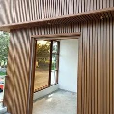 an empty room with wooden slats on the wall and windows in front of it