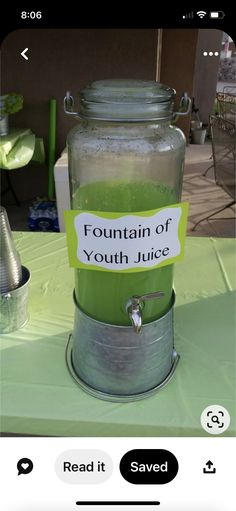 a jar filled with liquid sitting on top of a table next to a sign that reads fountain of youth juice