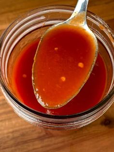 a spoon full of sauce sitting on top of a wooden table