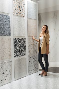 a woman standing in front of a wall with different types of tiles