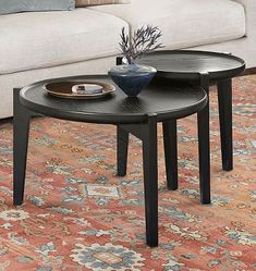 two tables sitting on top of a rug in front of a couch and coffee table