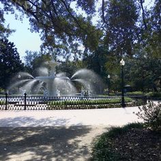 a fountain in the middle of a park surrounded by trees