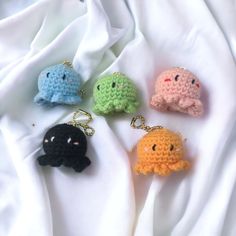 four crocheted keychains in different colors on a white sheet, with one black and one green