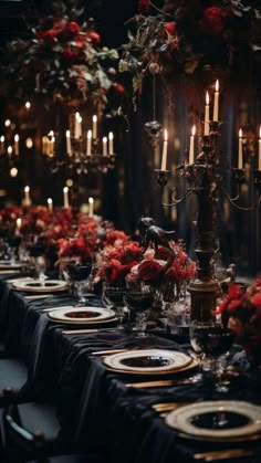 a long table is set with black linens, red flowers and candles in the center