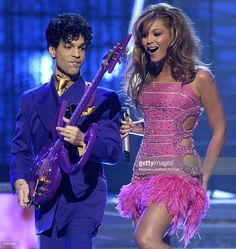 a woman in a pink dress standing next to a man with a guitar on stage