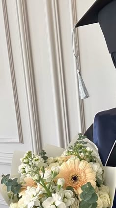 a bouquet of flowers sitting on top of a table next to a graduation cap and gown