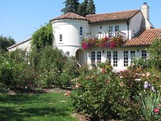 a white house surrounded by flowers and greenery