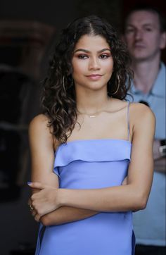 a woman in a blue dress with her arms crossed