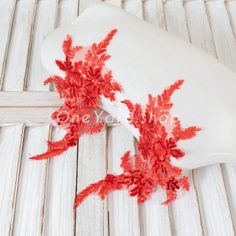 red flowers are placed on the back of a white pillow with wood slats in the background