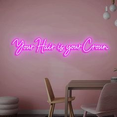 a pink wall with the words your hair is your crown on it and two chairs