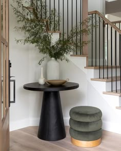 there is a plant in the vase on the table and two stools next to it