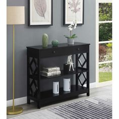 a black shelf with two pictures on the wall above it and a lamp next to it