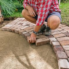 a man kneeling down to put bricks in the ground