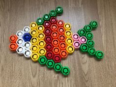 a colorful fish made out of crayons sitting on top of a wooden table