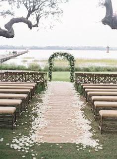 an outdoor ceremony set up with chairs and flowers on the aisle, along with greenery