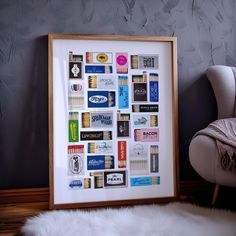 a white chair sitting next to a framed poster on a wall in front of a gray wall