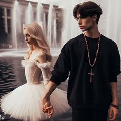 a man and woman standing next to each other in front of a fountain