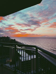 an ocean view from the balcony of a hotel room at sunset or dawn with pink and blue clouds