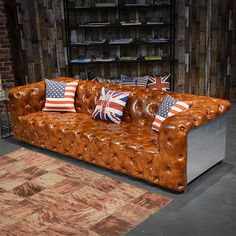 a leather couch with pillows on it in front of a brick wall and rugs