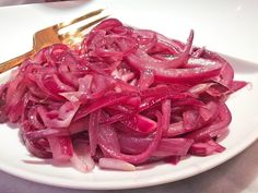 a white plate topped with red onions next to a fork