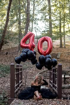 a woman is sitting on the ground with balloons in front of her, that say 40