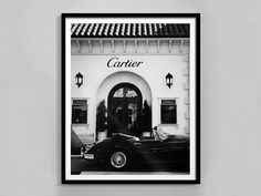 a black and white photo of a car parked in front of a building