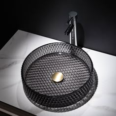 a round glass sink on top of a white counter with a black faucet