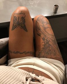 a person with tattoos on their legs laying down