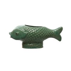 a green fish shaped vase sitting on top of a table