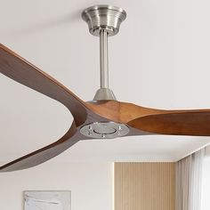 a modern ceiling fan with wooden blades in a living room or dining room area by a window