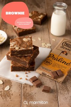 three pieces of brownie sitting on top of a white plate next to a carton of milk