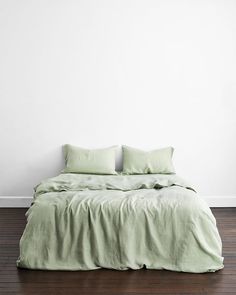 a bed with two pillows on top of it in a room that has hardwood floors