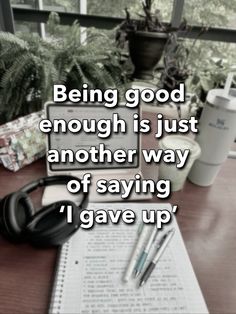 a desk with headphones on it and a notepad in front of the words being good enough is just another way of saying i gave up