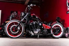 a red and black motorcycle parked in a garage next to a skateboard on the ground