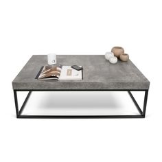 a concrete coffee table with two candles on top and an open book next to it