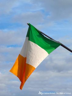 an irish flag flying in the wind on a cloudy day with blue sky and white clouds