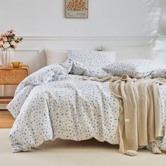 a bed with blue and white flowers on it in a room next to a table