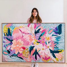 a woman standing in front of a large painting with pink and blue flowers on it