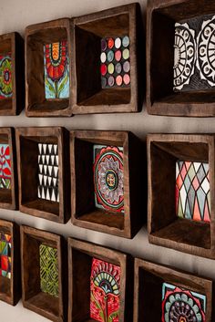 several wooden boxes with designs on them hanging on a wall in a room that has white walls