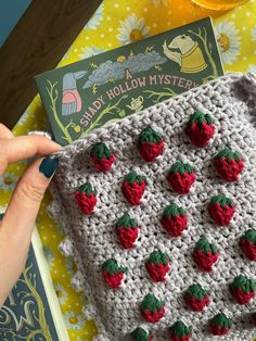 a crocheted granny blanket with strawberries on it and a book about candy