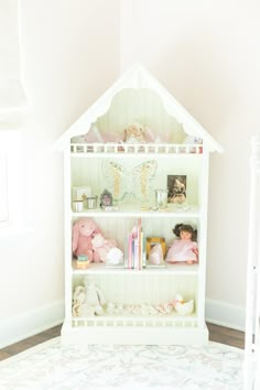 a white doll house shelf with stuffed animals