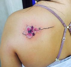 the back of a woman's shoulder with a flower tattoo on it