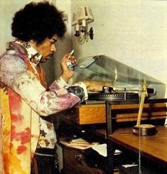 a man standing in front of a desk writing on a piece of paper next to a record player