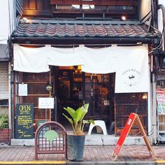 the outside of a restaurant with an open sign and potted plant