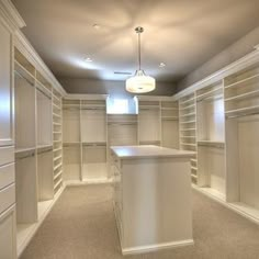 an empty walk - in closet with white cabinets and countertop space for the bar