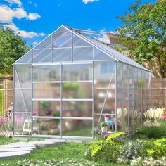 a small greenhouse in the middle of a garden with flowers and plants growing inside it