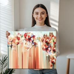 a woman holding up a painting with flowers on it